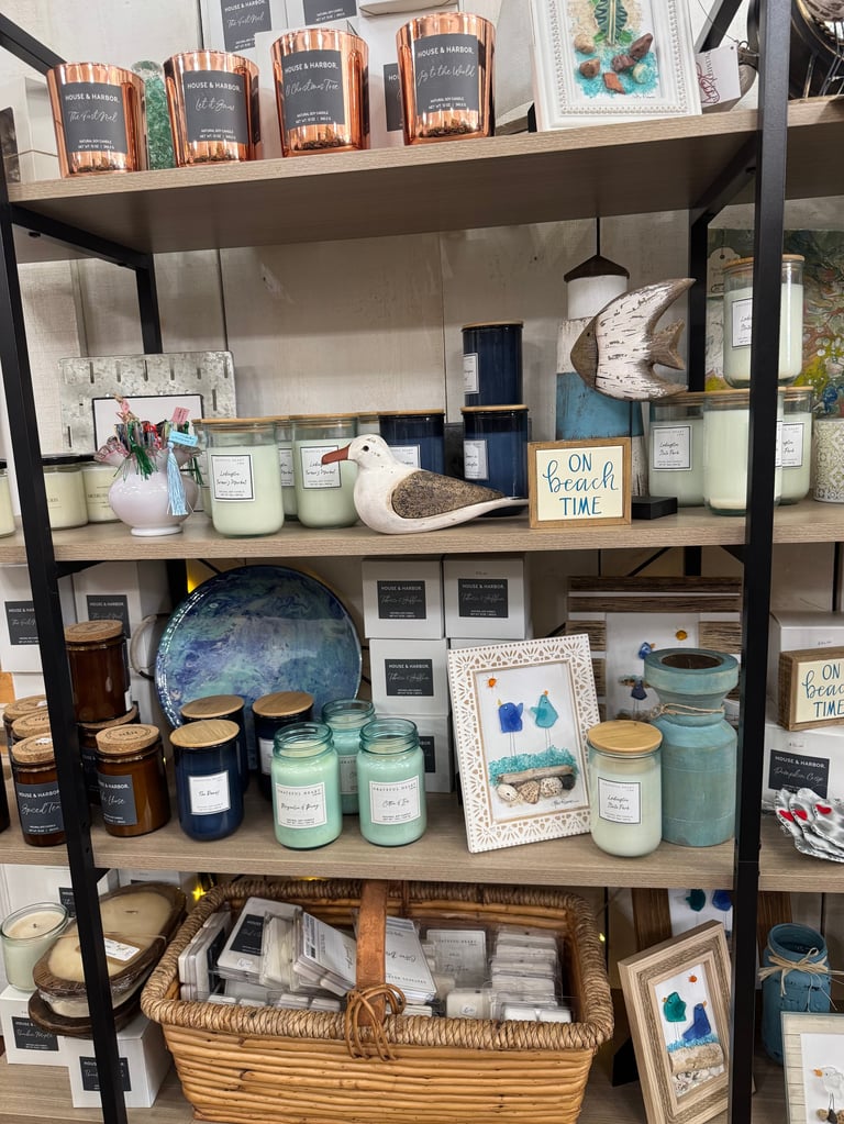Black metal shelving unit displaying scented candles, ceramic jars, decorative items, and home décor products arranged on four shelves