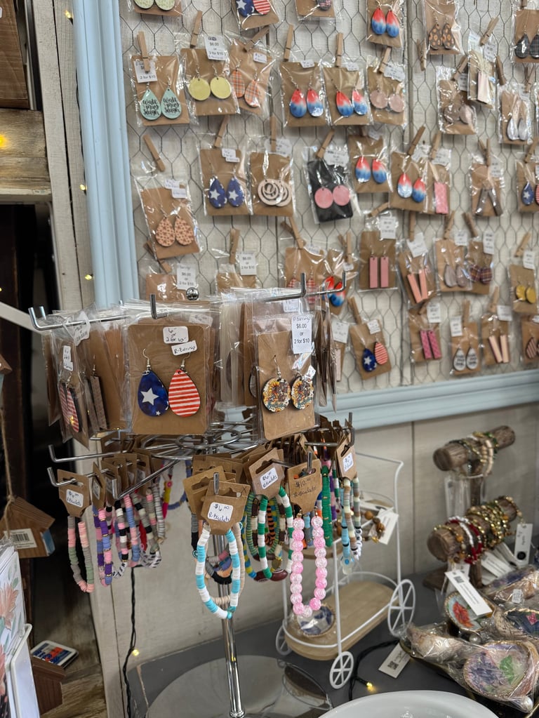 Retail display of handmade wooden earrings and beaded jewelry hanging on pegboard and stands with price tags