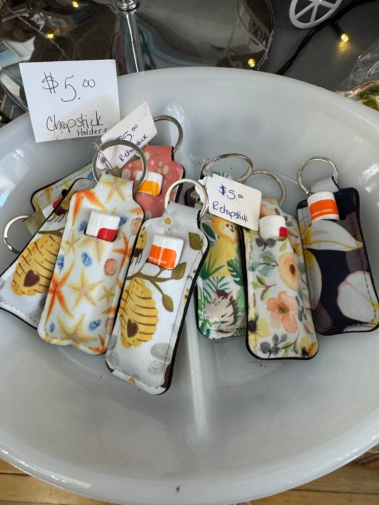 Colorful fabric keychains arranged in a white bowl with price tags. Multiple small pouches with floral and geometric patterns displayed for sale at $5.