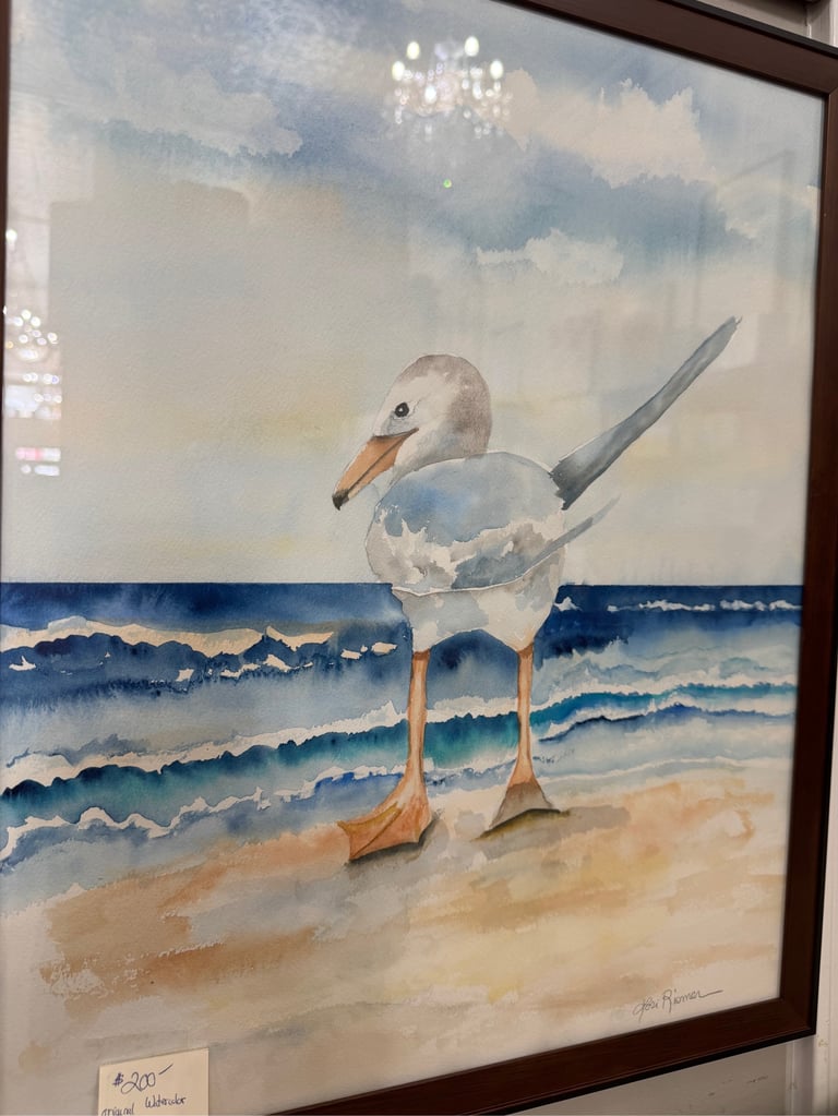 Watercolor painting of a seagull standing on a sandy beach with ocean waves in the background